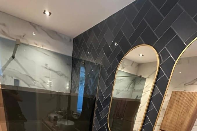 Dubbele wastafels met marmerlook en gouden kranen in een badkamer van Refix