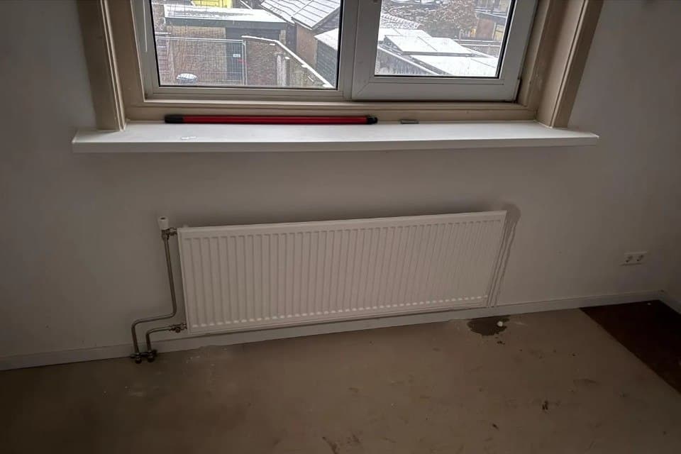 Nieuw geplaatste radiator met leidingwerk tijdens renovatie
