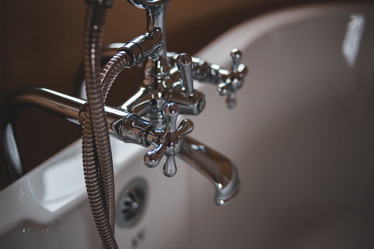 Chroomen badkraan op een wit bad, sfeerbeeld van een waterinstallatie